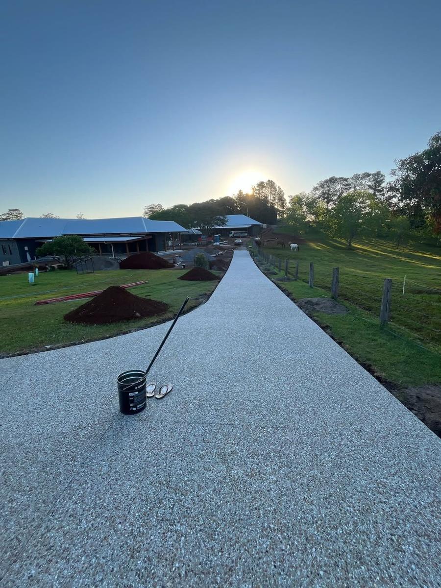 Long exposed aggregate acreage driveway beside a paddock at sunrise