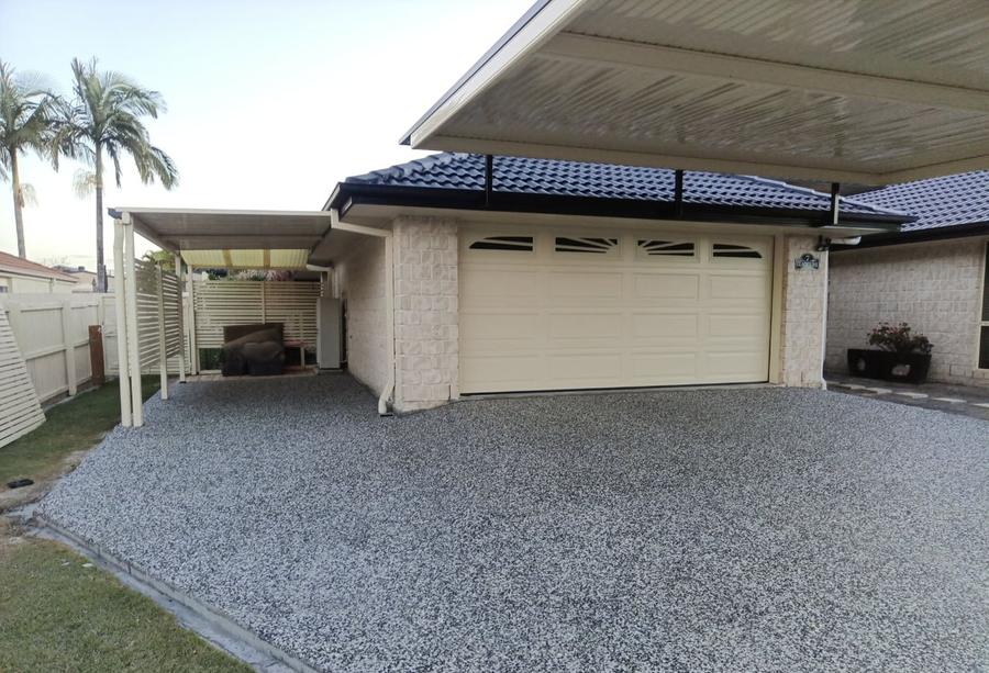 Exposed aggregate apron in front of a double garage and side carport