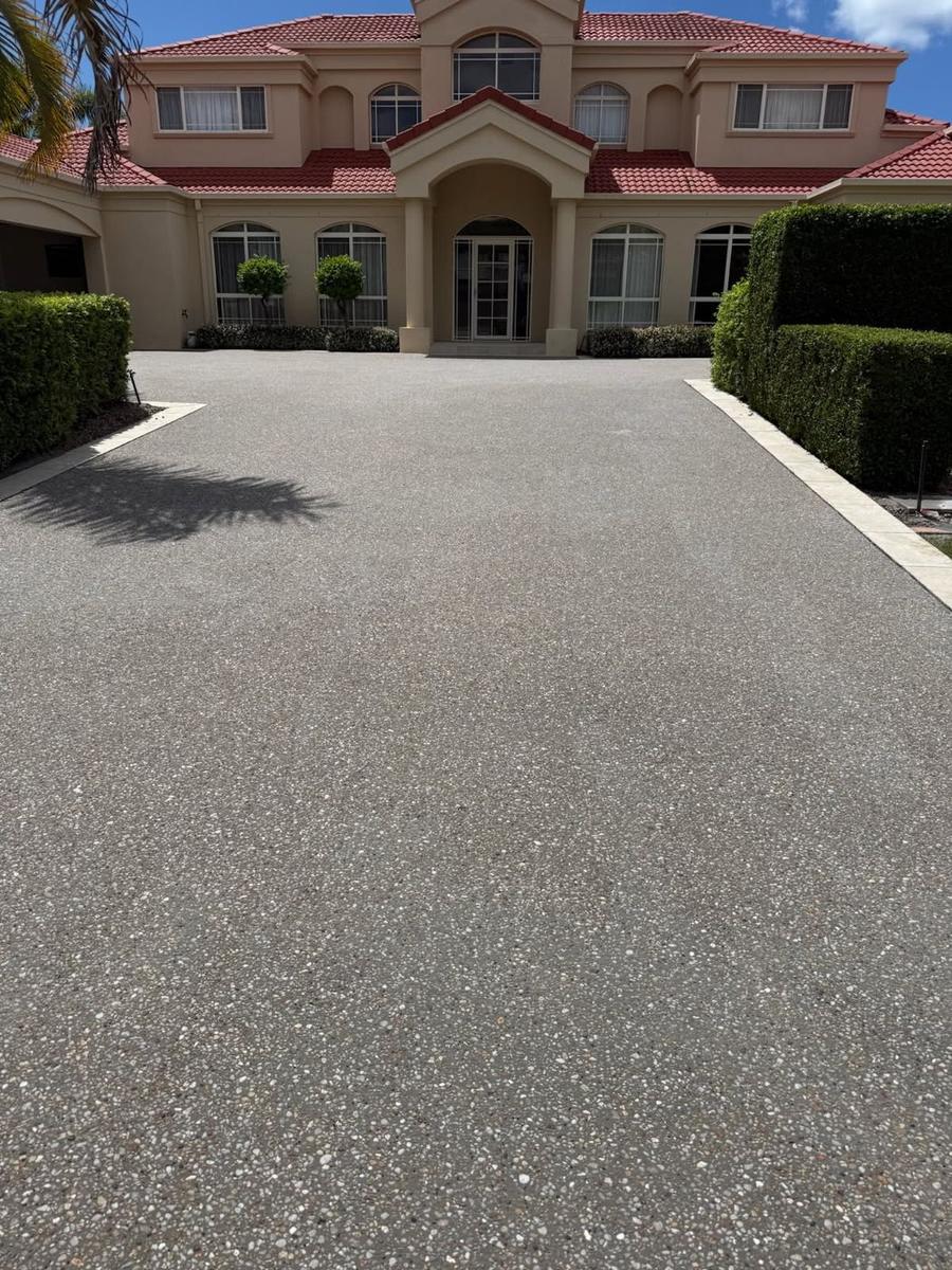 Broad exposed aggregate driveway in front of a large two-storey home