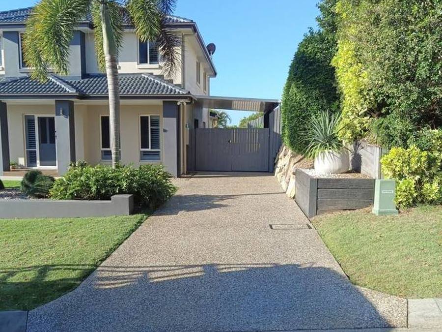 Exposed aggregate driveway leading to a gated carport